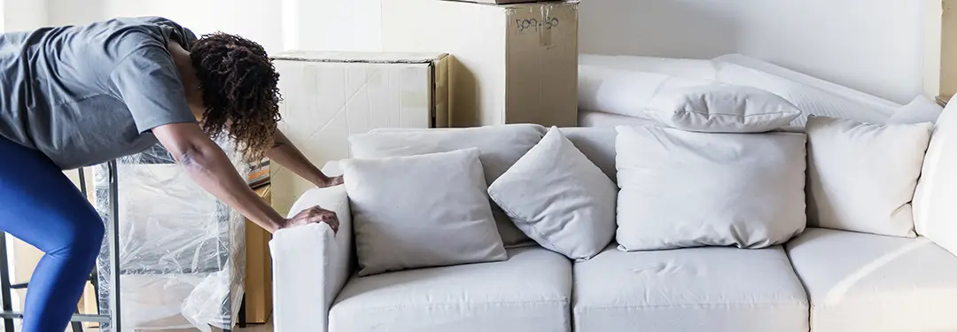 Keske Umzüge Schwere Möbel sicher transportieren Frau schiebt graues Sofa
